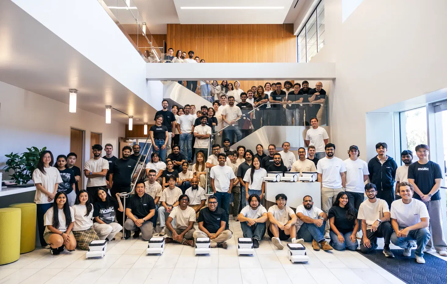 The Matic team gathered together with a row of robots in front