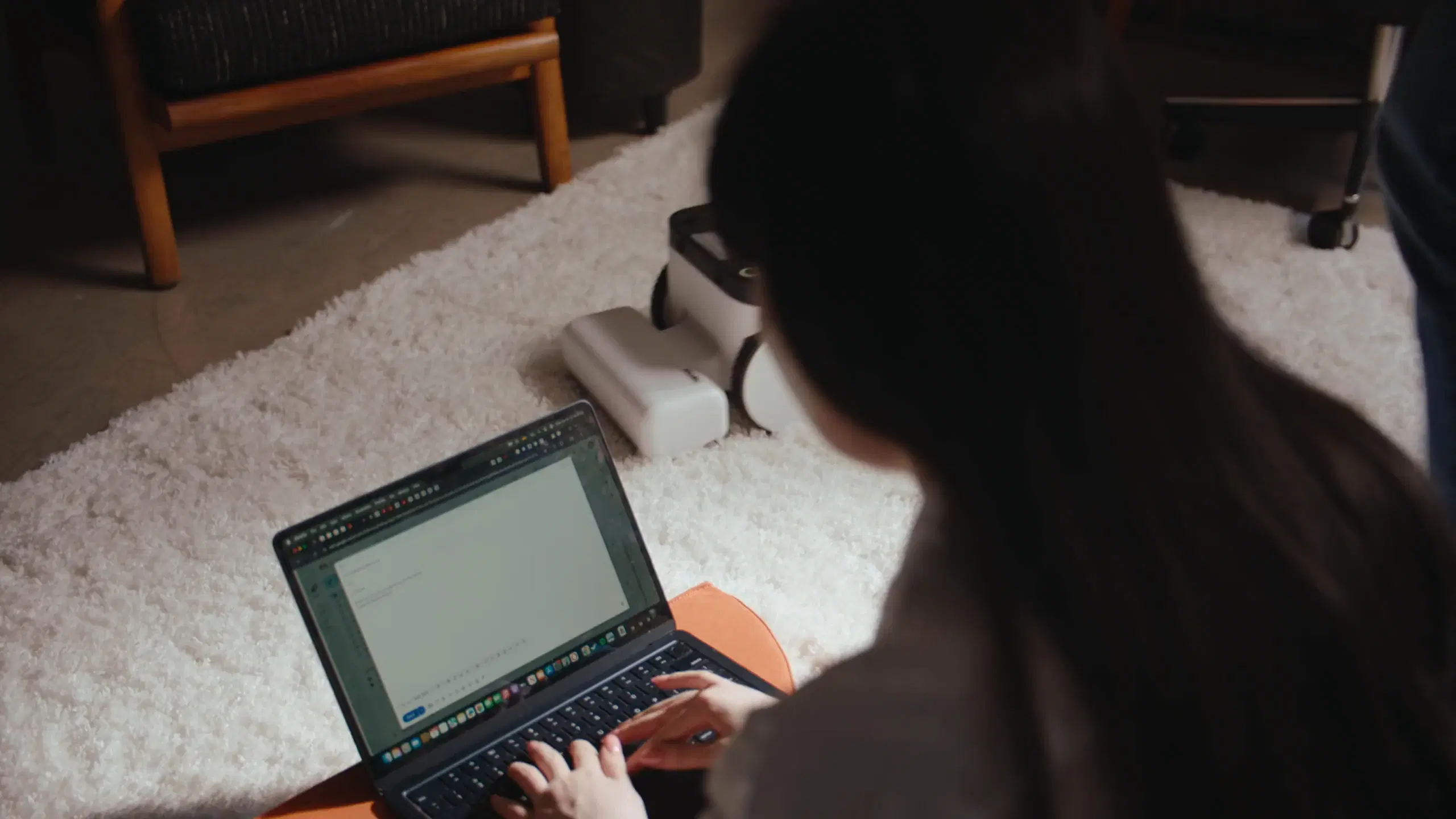 Someone working at a laptop while Matic sits on the rug beside them